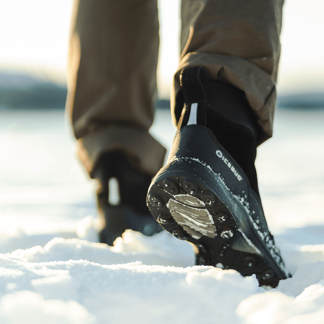 a person walking in snow with a pair of black winter boots from Icebug