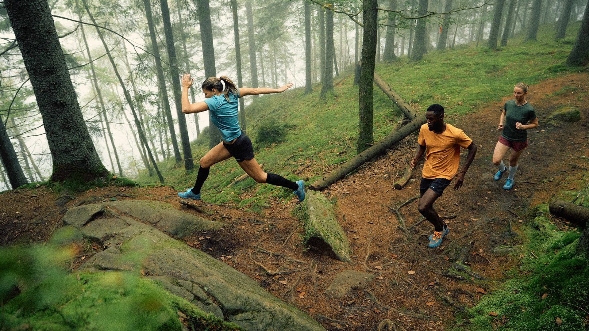 Three friends running on a trail in the woods, enjoying the fresh air and the beauty of nature.